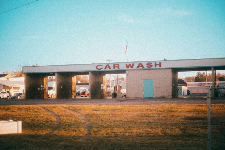 a small, white car wash building with large windows