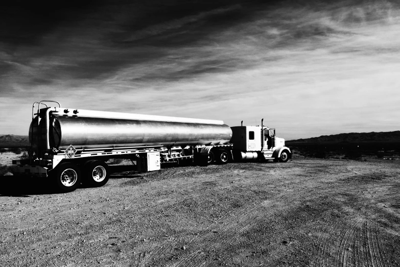 two semi trailers are lined up on the dirt road