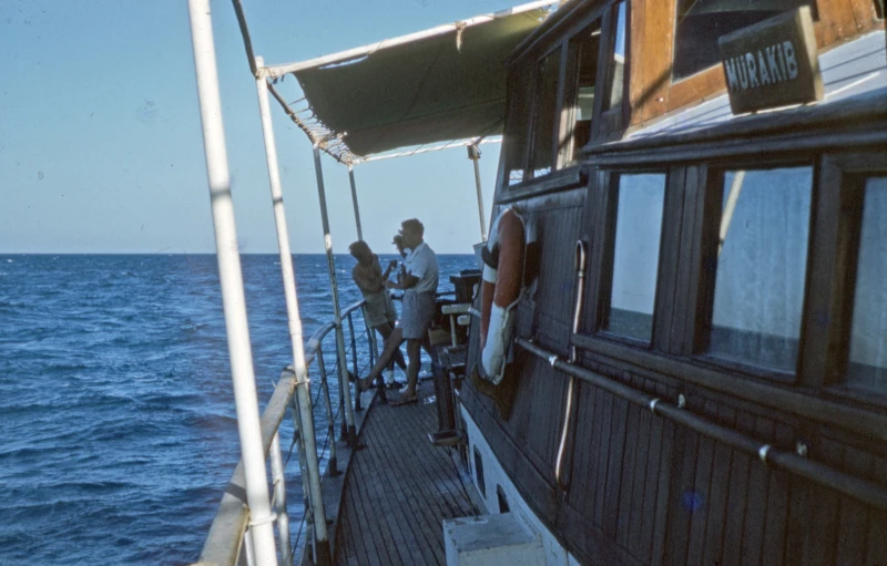 people standing on the bow of a boat on the water