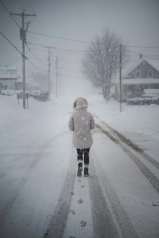 child in winter clothing walking on snow covered street