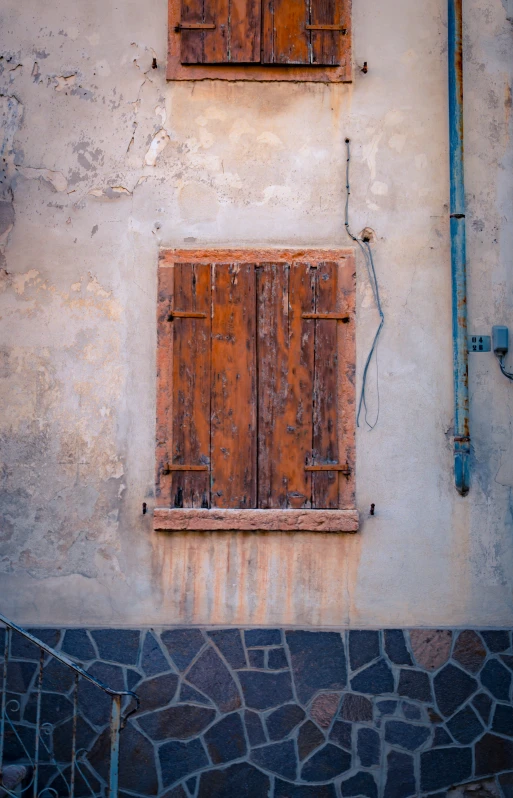 two wooden windows, with some rusty bars hanging above