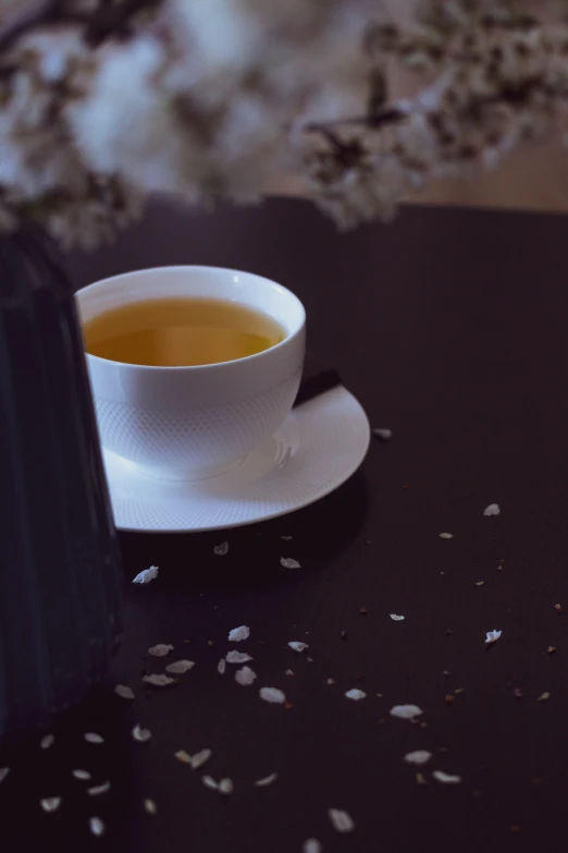 a cup and saucer on a table with some white leaves