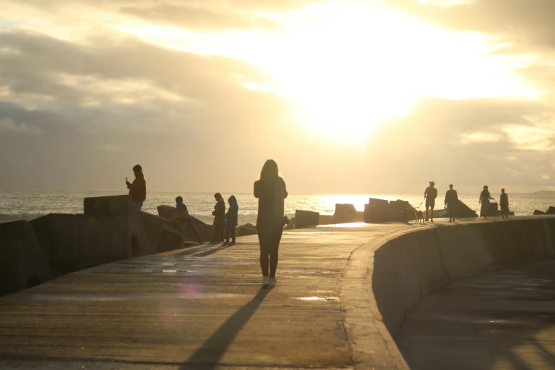 a group of people walking down a sidewalk near the ocean