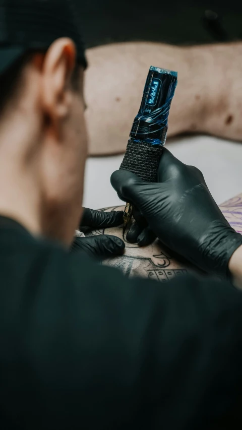 a tattooist working on a machine on someones arm