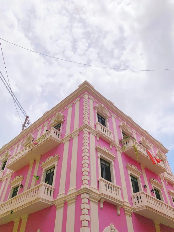 pink and white building with balconies on top of it