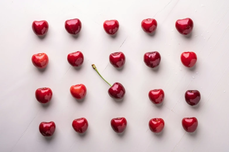 a bunch of cherrys on a white table with a one piece taken out