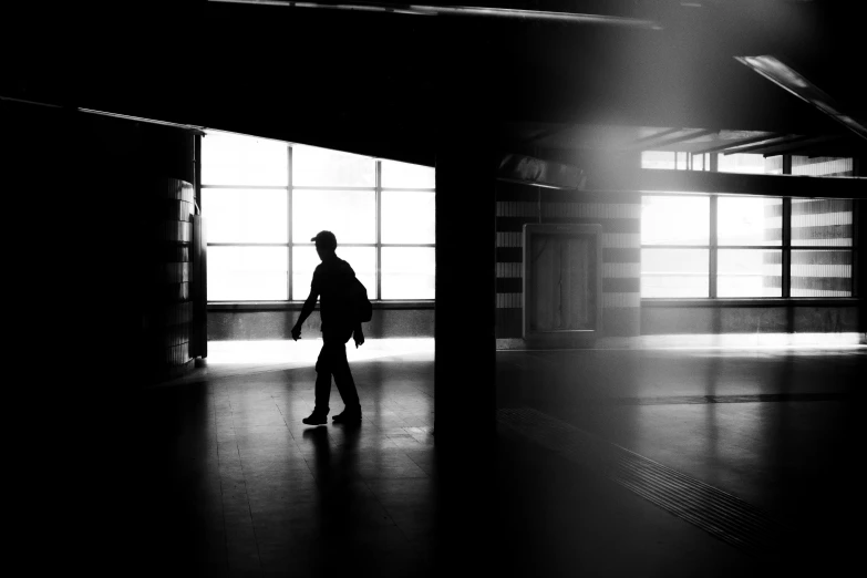 a man walking towards a window in an empty building