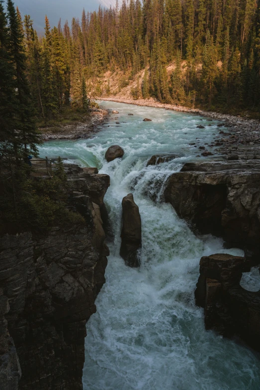 the river is rushing down a hillside among large rocks