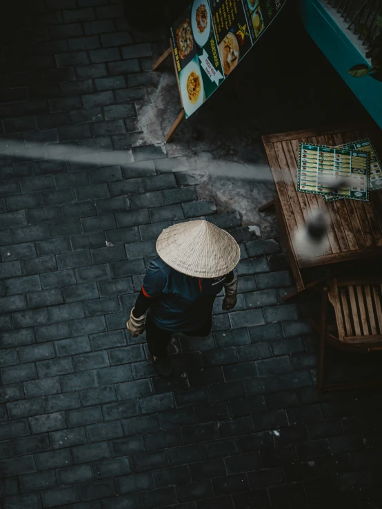 an overhead view of a person with a straw hat near an outdoor table