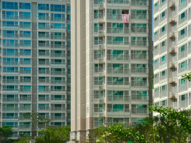 the building is next to another tall building and has green windows