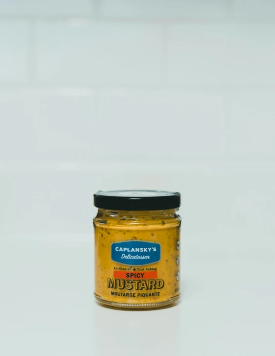 a jar of mustard sitting on a white countertop