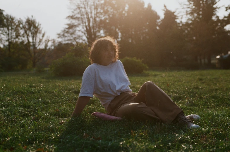 a girl sitting in the grass looking to her right