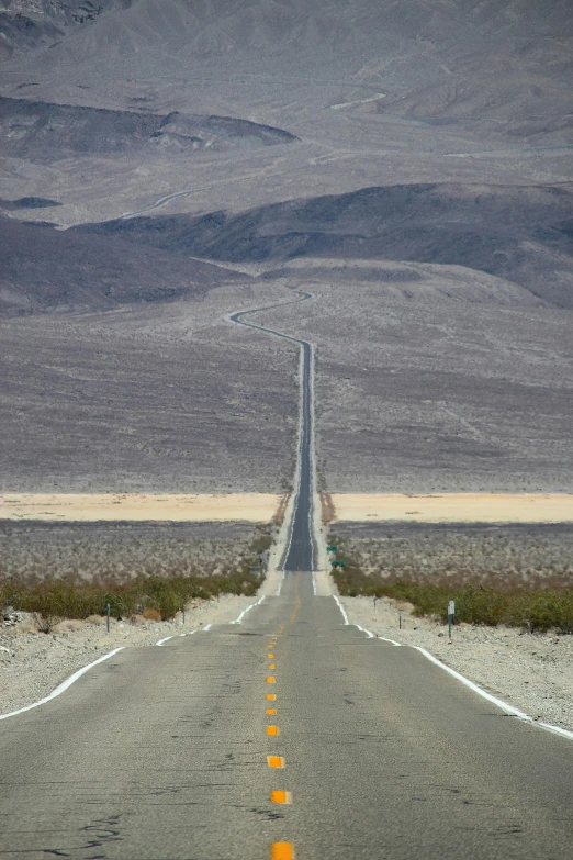 a single long straight road in the middle of a field