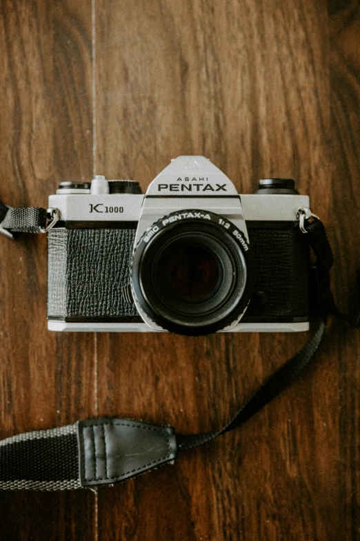 a old camera on a wooden table with straps