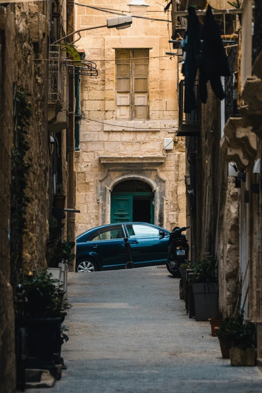 car is parked at the end of a narrow cobblestone street