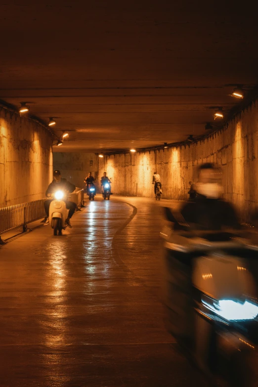 people ride motorcycles through an underground tunnel