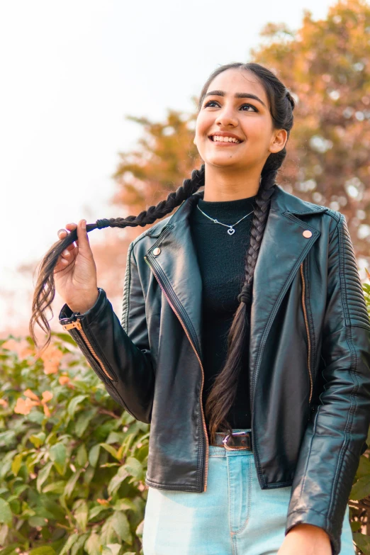 a young woman in a leather jacket smiles and poses for the camera