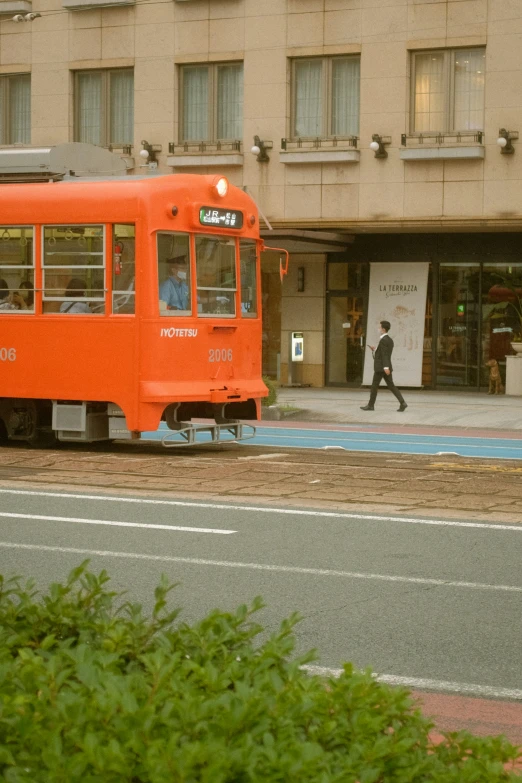 an orange train pulling into a station on tracks