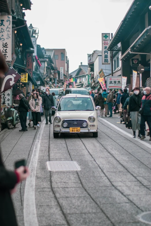 the car is driving down the road among the crowd