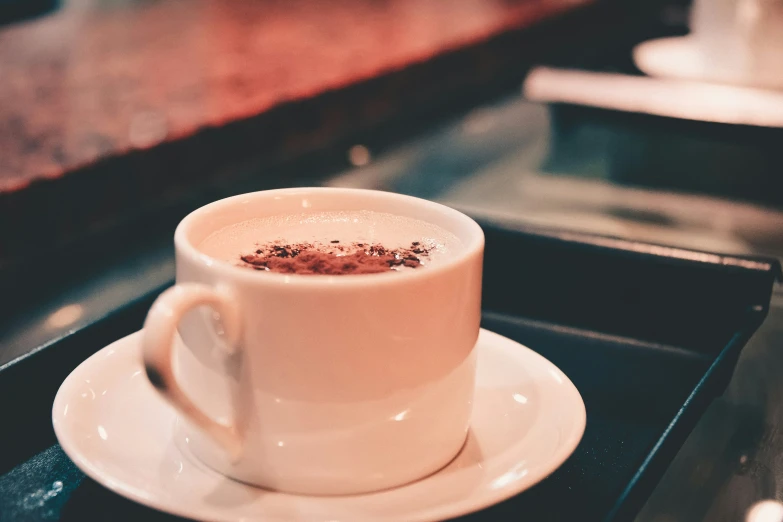 a cup on a saucer sits on a black tray