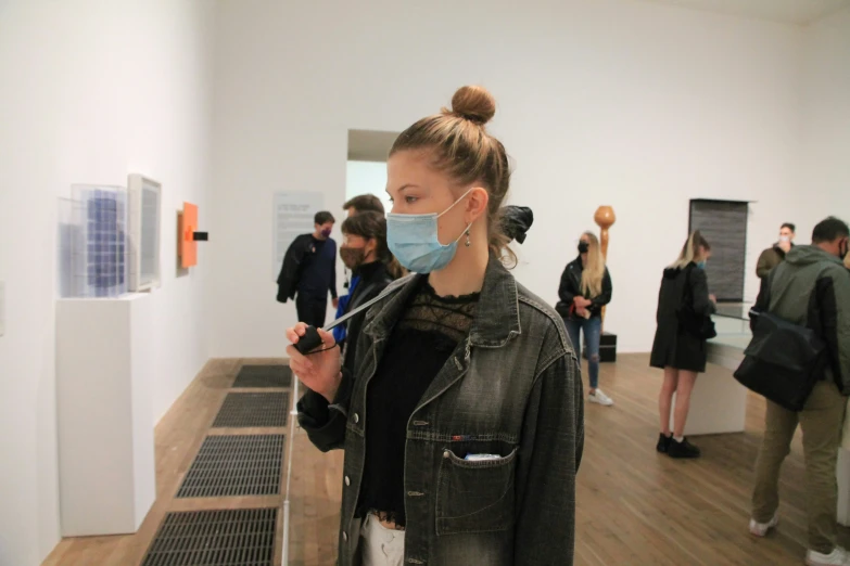 a woman wearing a surgical mask in an art gallery