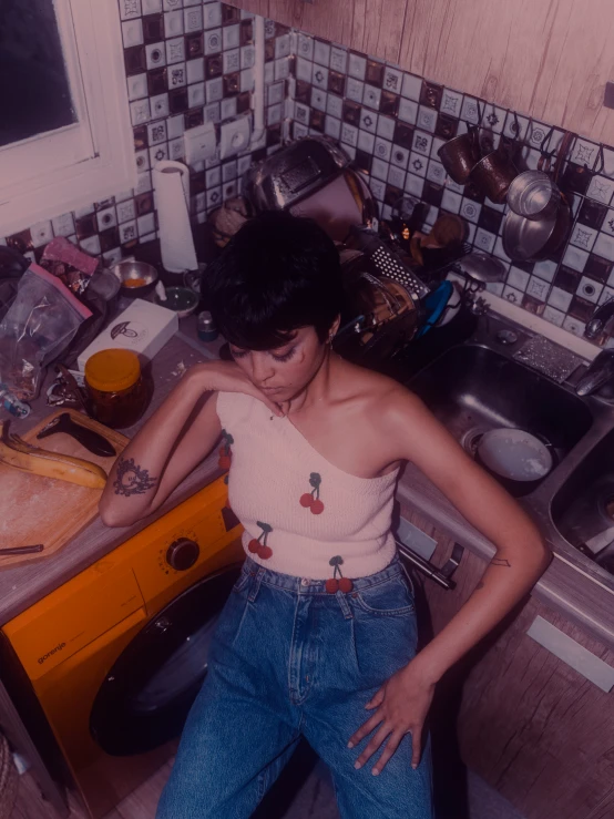 a girl stands in the middle of a messy kitchen counter