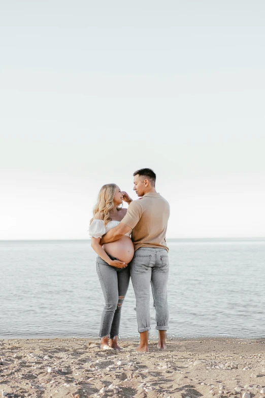 a couple cuddles on the beach as the water sprays behind them