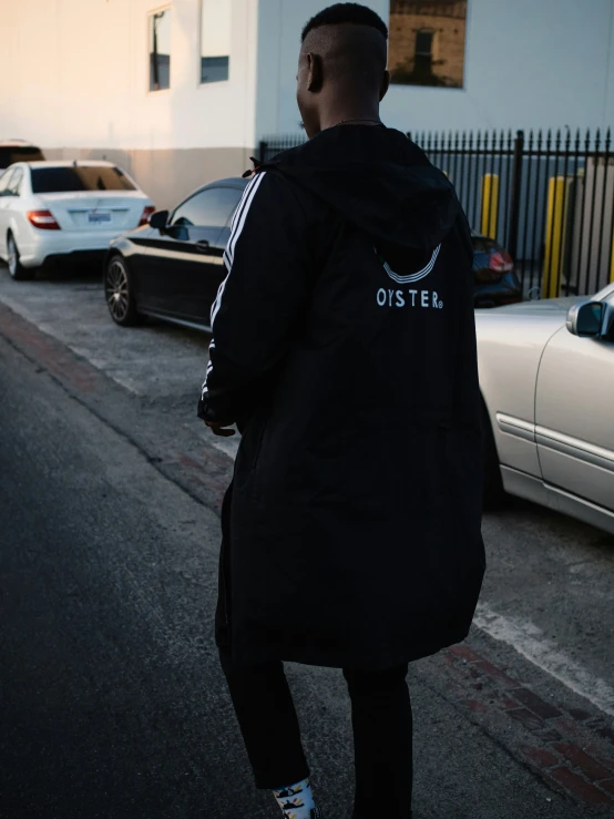 a man walks down the street wearing a black hoodie