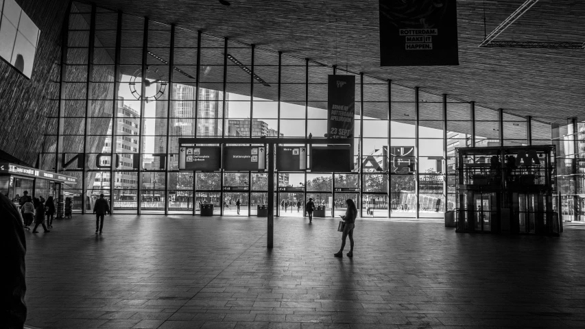 people walking inside a covered shopping area with many windows