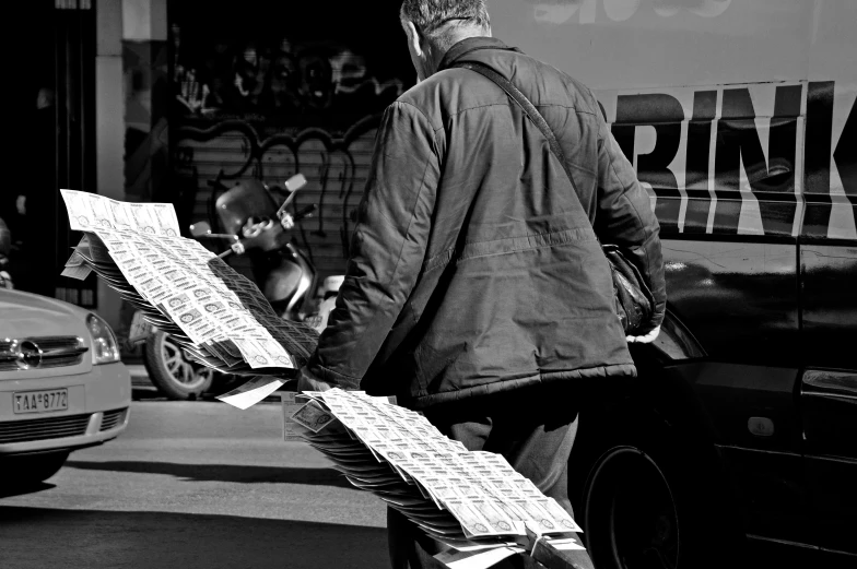 man walking down a street carrying a large piece of newspaper