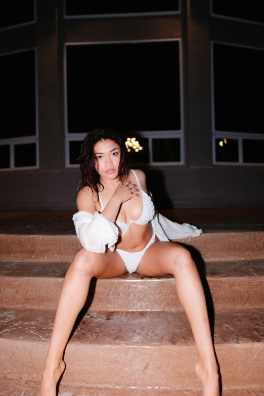 a woman in white lingerie sitting on steps