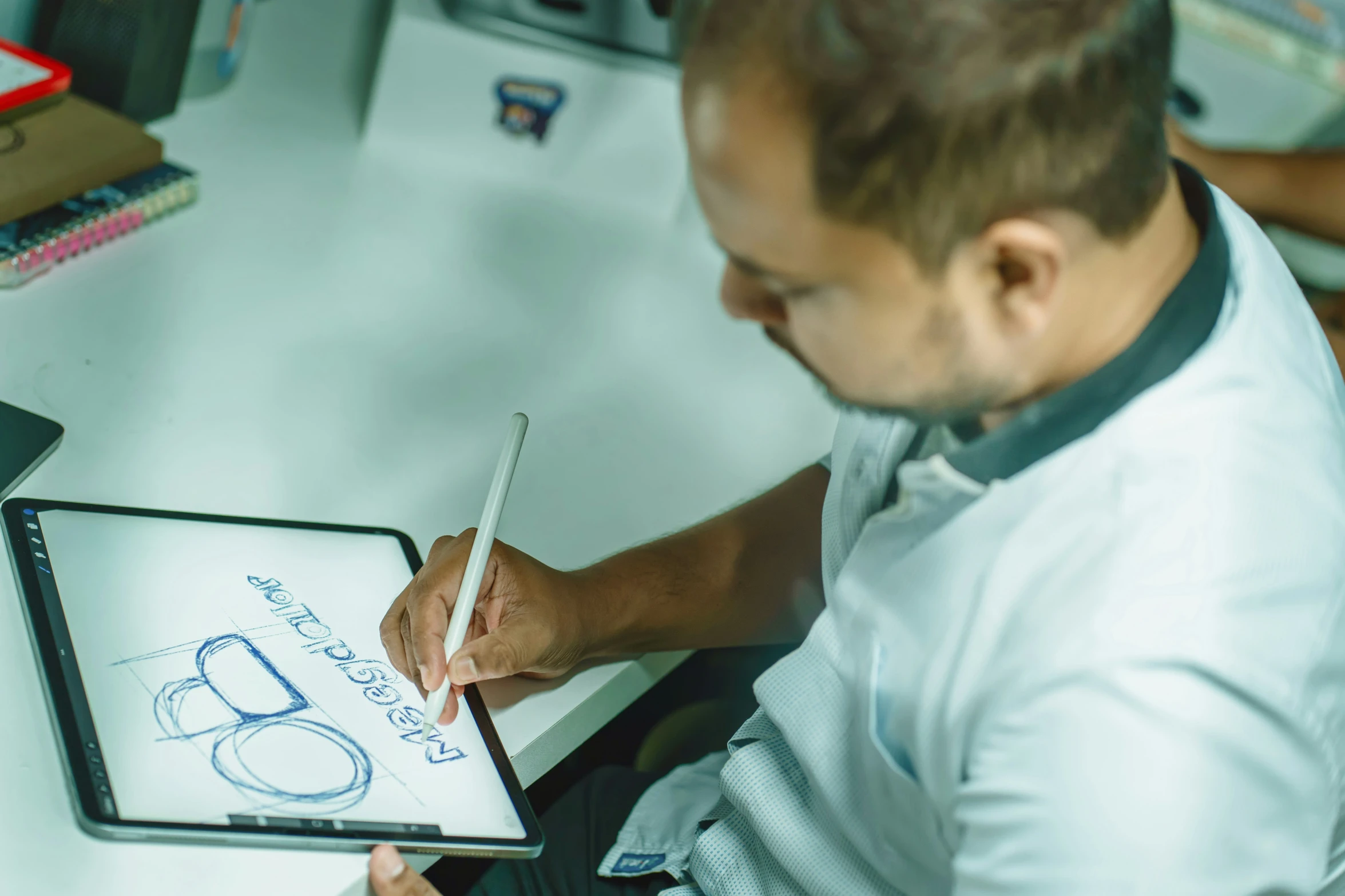 man in white shirt holding tablet with drawing and writing on it