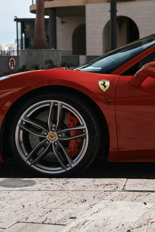 a red ferrari with a black face is parked in front of a building