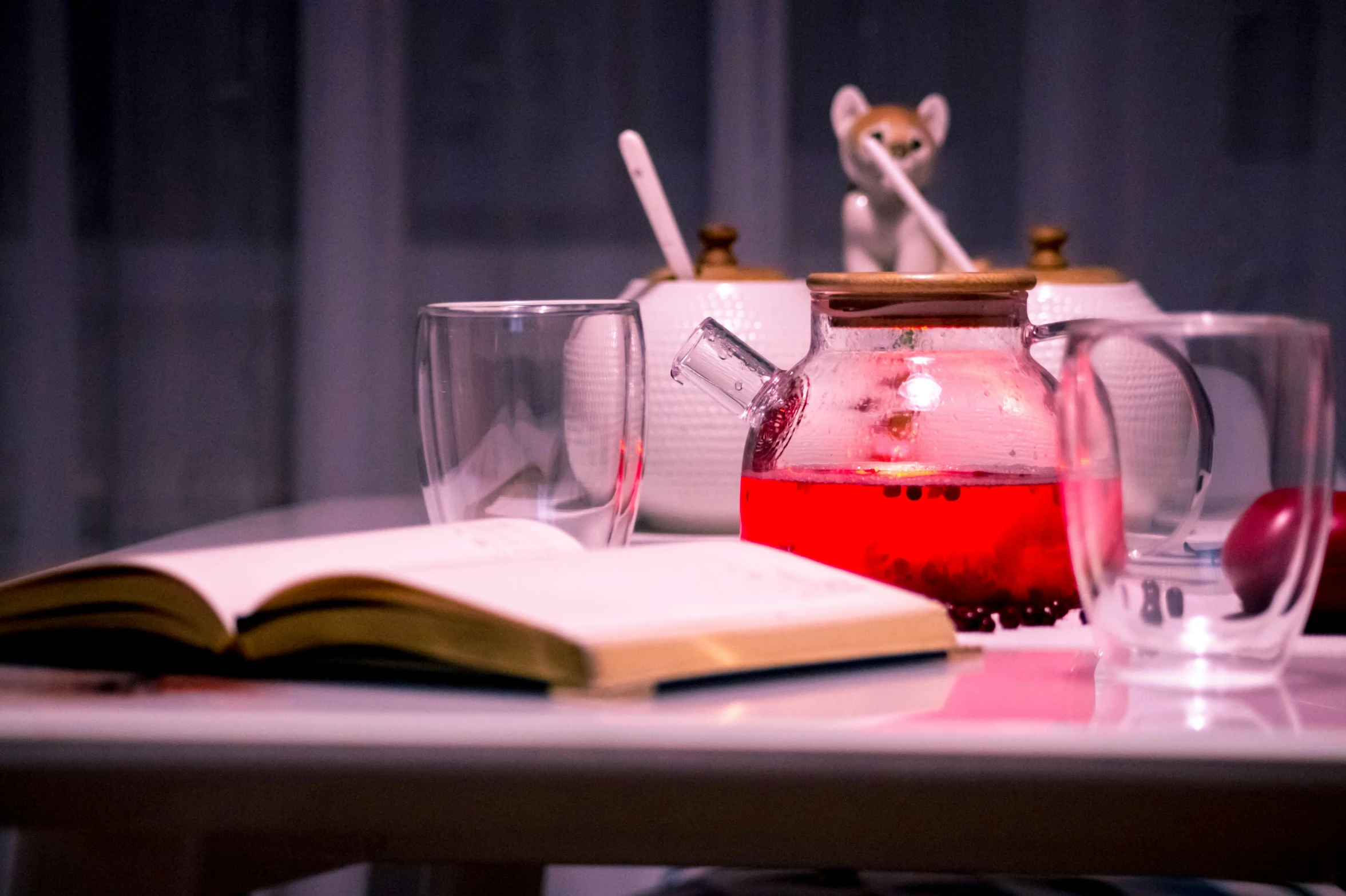 the table has a pitcher, glasses, and a book on it