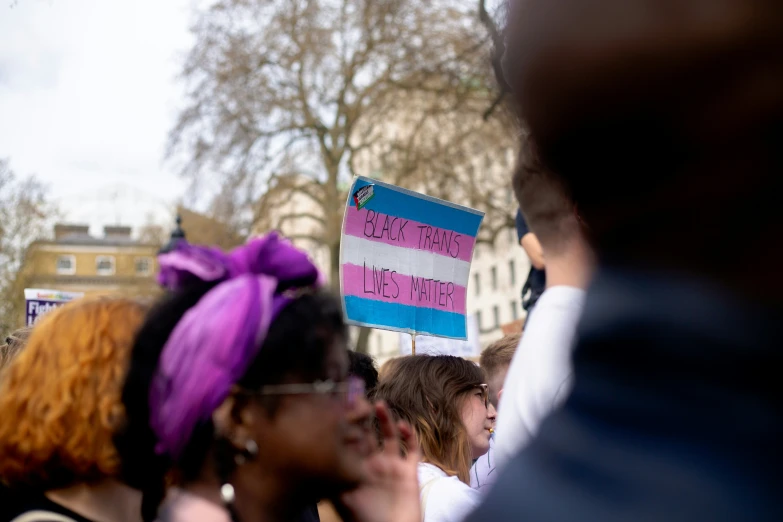 woman at rally holding a pink and blue sign with writing on it