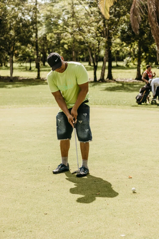 man putting ball in the hole of golf course