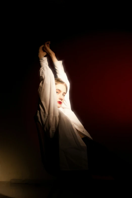 woman in veil performing with hand raised and red background