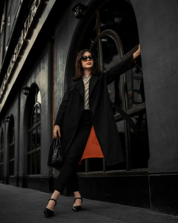 a woman walking along the sidewalk while holding onto an orange piece of material