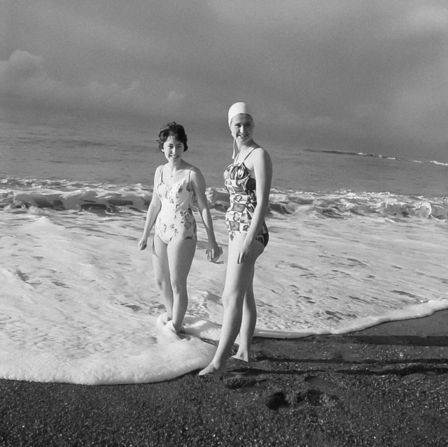 two children standing on the shore of a beach