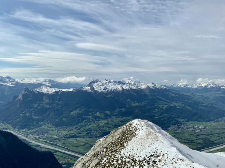 a snow covered mountain with green grassy and mountains below