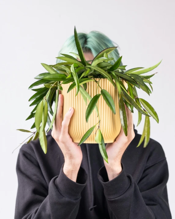 a person is covering their face with a green plant