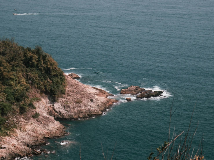 a boat is sailing in the ocean with trees on the shore