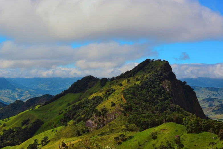 a large mountain with green hills and hills behind it