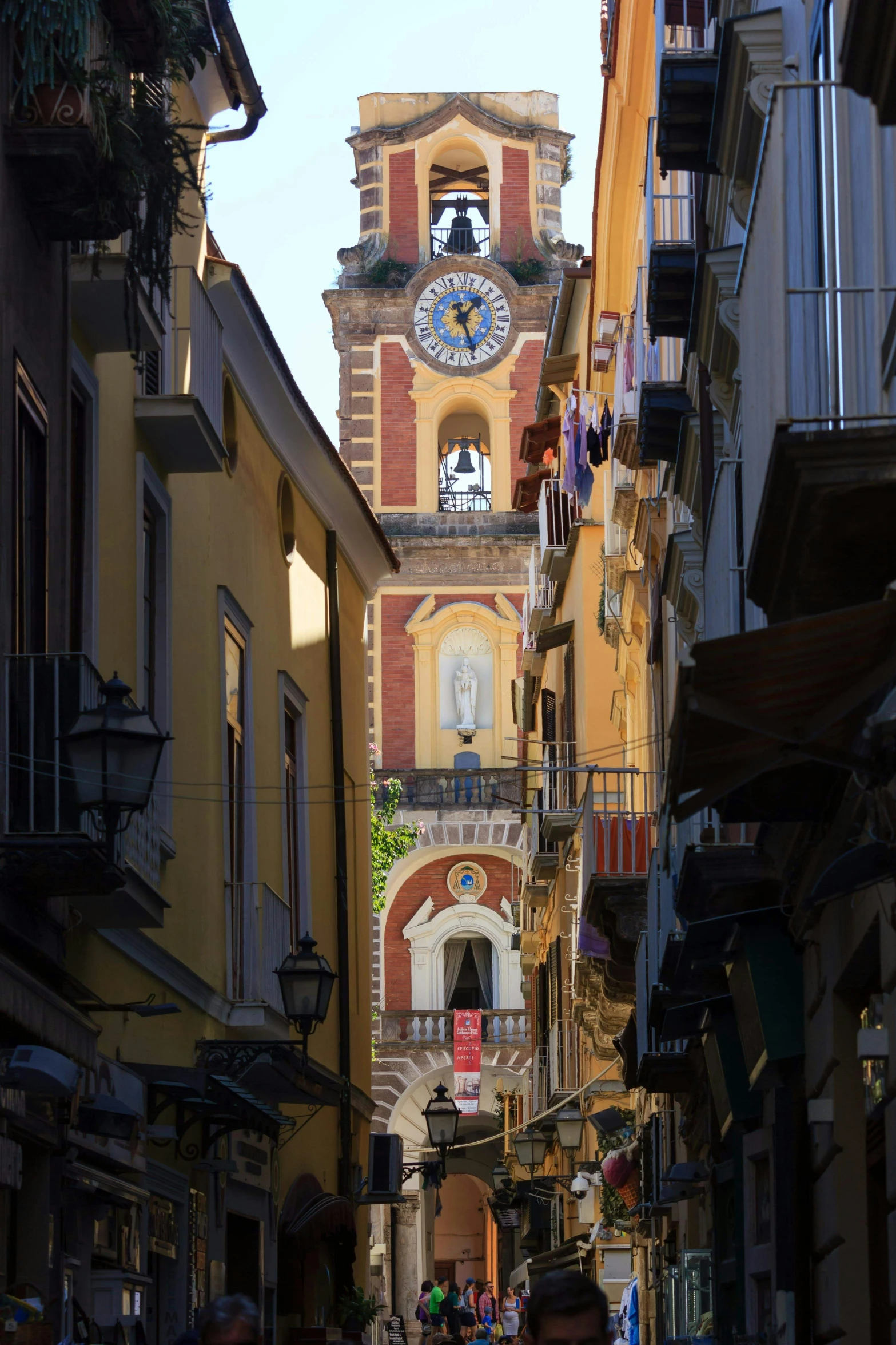 street with old buildings and pedestrians walking past a clock tower