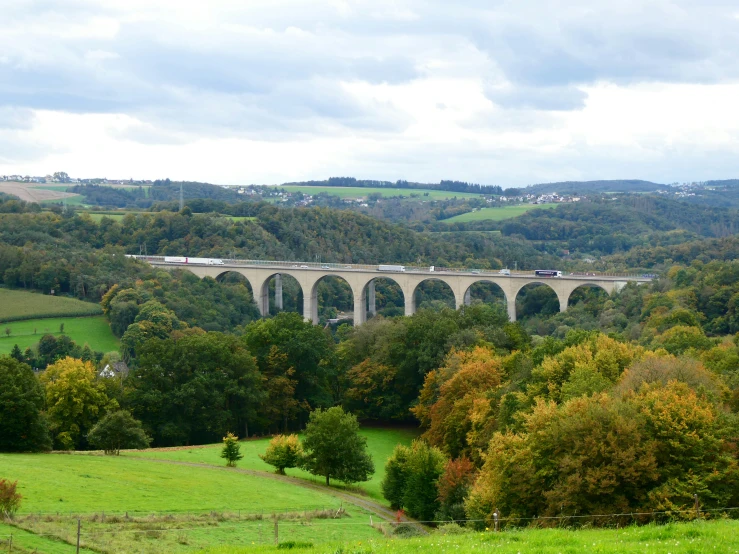 a scenic scene of a train passing over an arched bridge