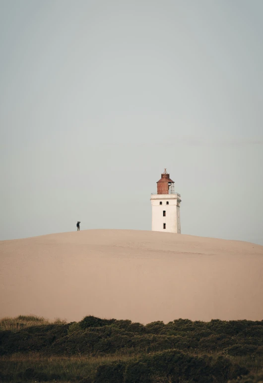 a lighthouse is pictured on a sand hill