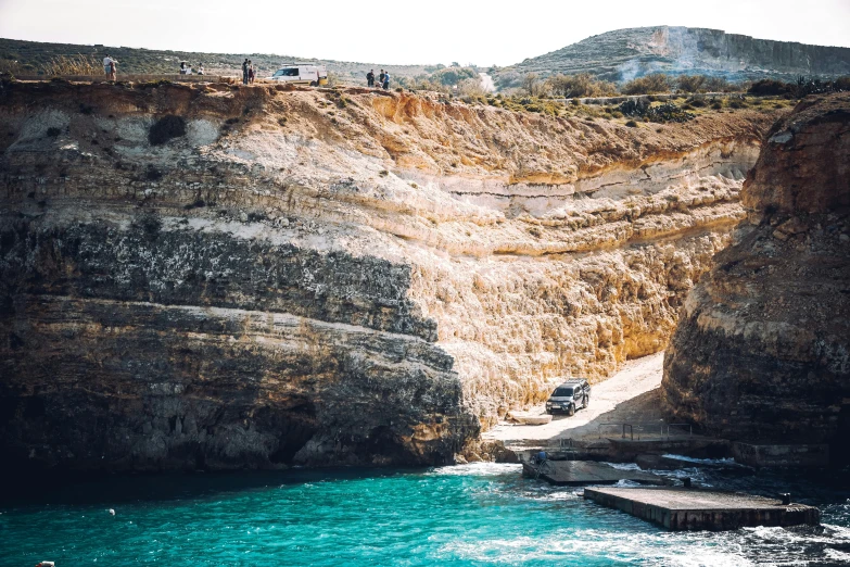 a group of people sitting on top of a cliff near the ocean