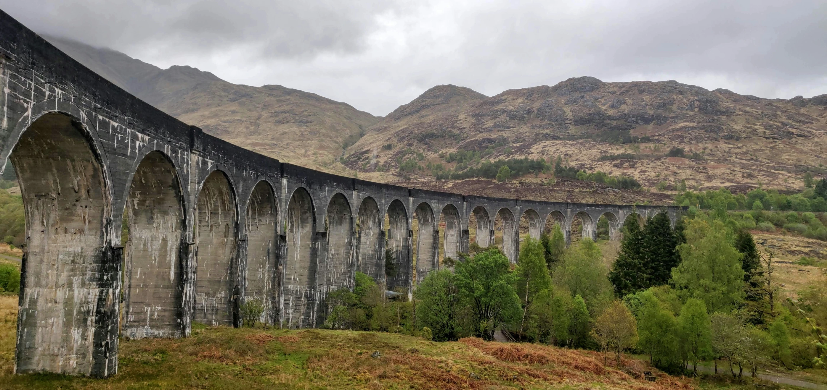 a long train is passing under a very tall bridge