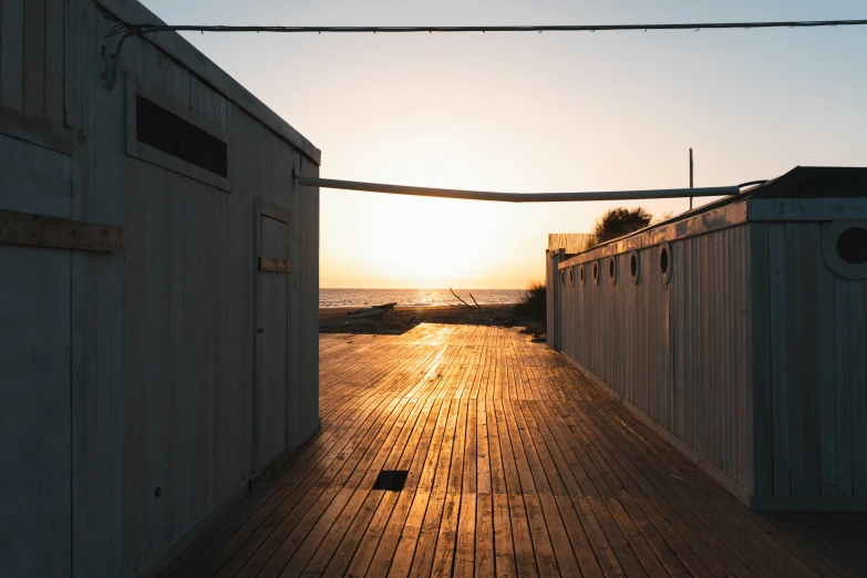 the sun rising over an ocean with a pier attached