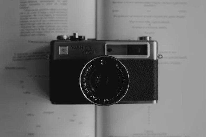 a book with pages open revealing a black and white po of an antique camera